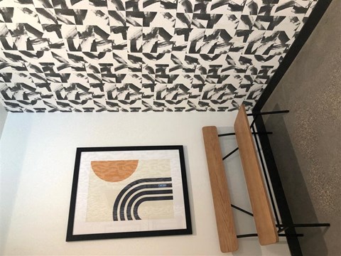 a white wall with a picture and some wooden dowels and a patterned ceiling