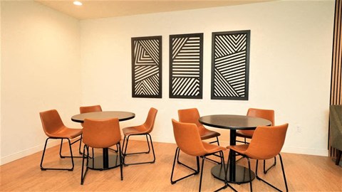 a room with tables and chairs and three paintings on the wall