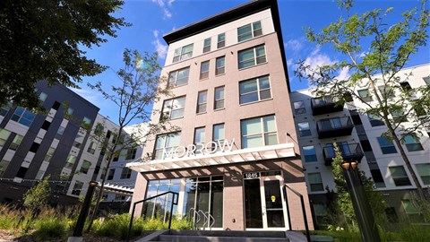 a tall building with a balcony and trees in front of it