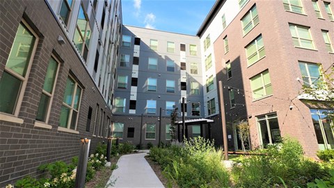 a pathway between two tall buildings with green plants