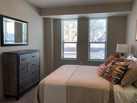 a bedroom with a bed and a dresser and three windows