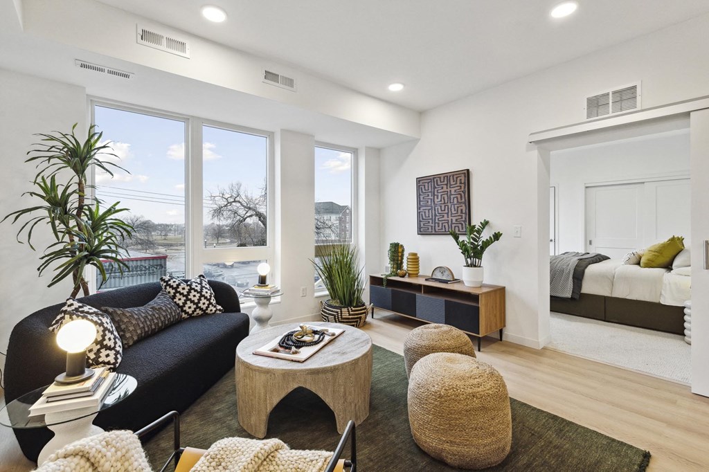 A living room with a black couch, a coffee table, and a large window.