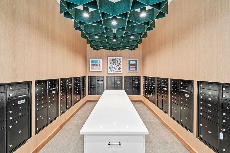 A long white table is in the middle of a room with black filing cabinets on both sides.