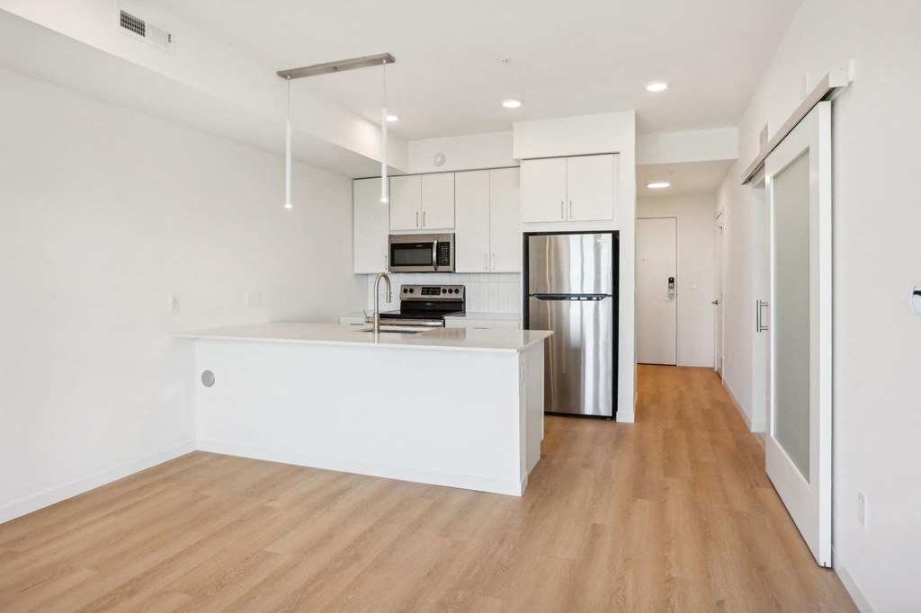 A kitchen with stainless steel appliances and wooden floors.