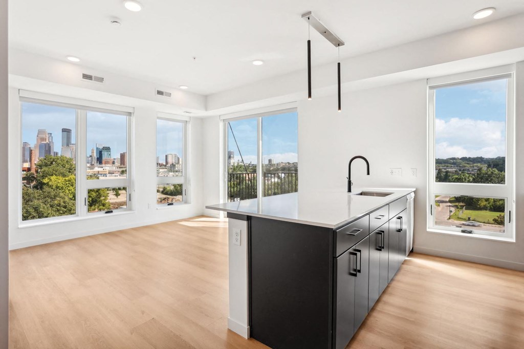 A kitchen with a black counter and cabinets with a view of the city.