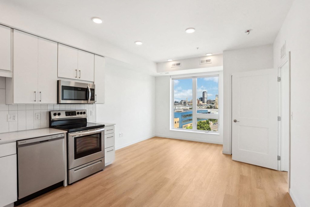 A kitchen with stainless steel appliances and wooden floors.