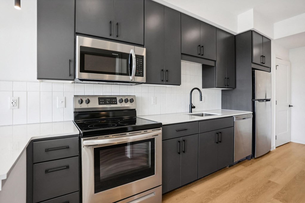 A modern kitchen with black cabinets and stainless steel appliances.