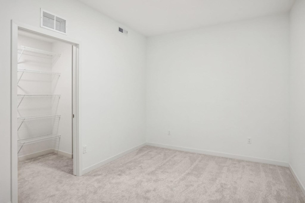 A white room with a door and a shelf.