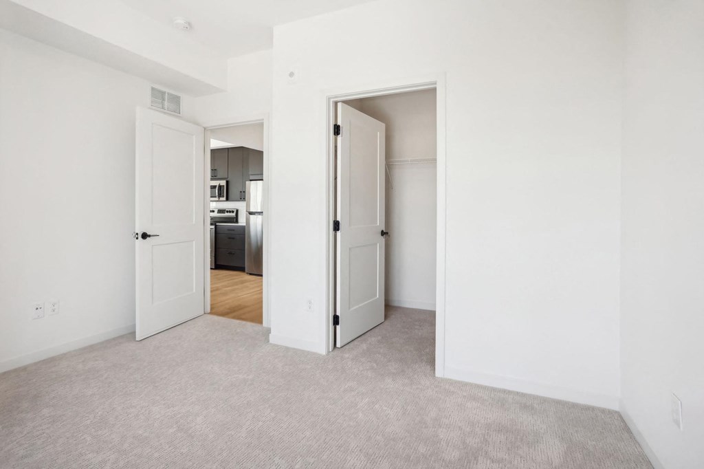 A white room with a carpeted floor and two open doors.