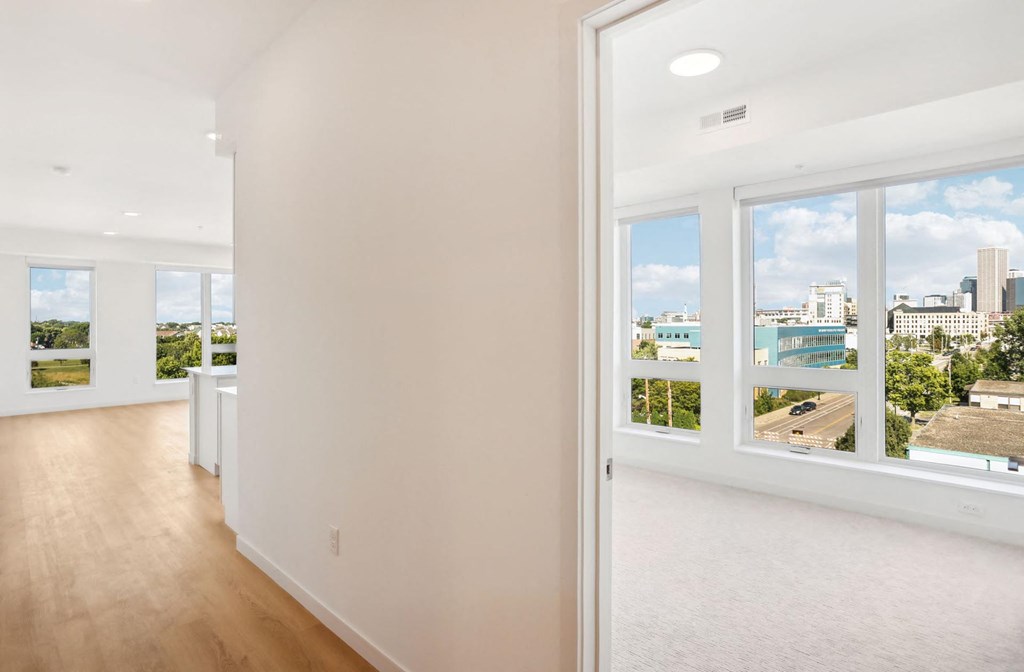 A white room with a view of the city through the windows.