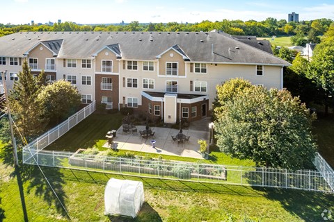 A large apartment complex with a fenced in yard and a tree.