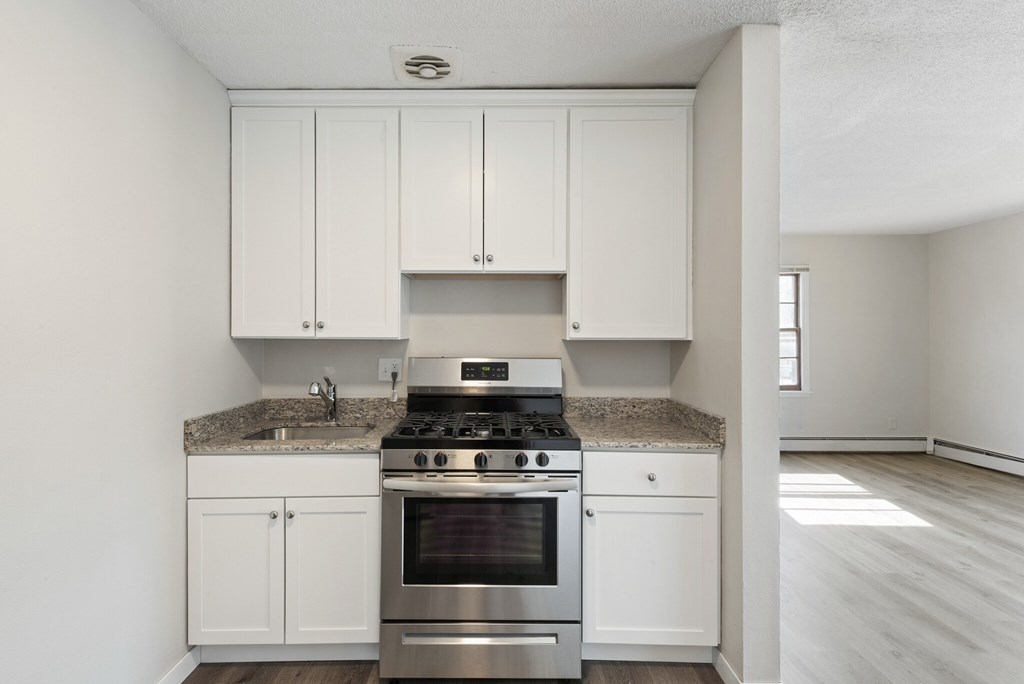 A kitchen with white cabinets and a granite countertop.