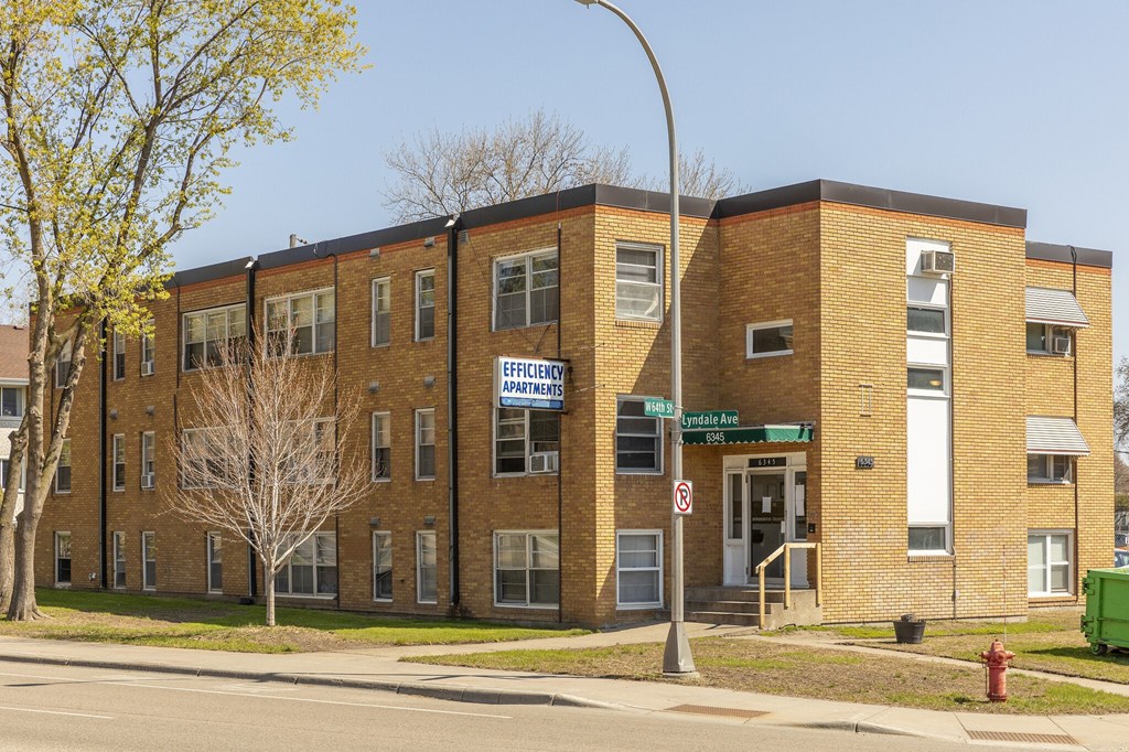 A multi-story brick building with a sign that says "Efficiency Apartments.".