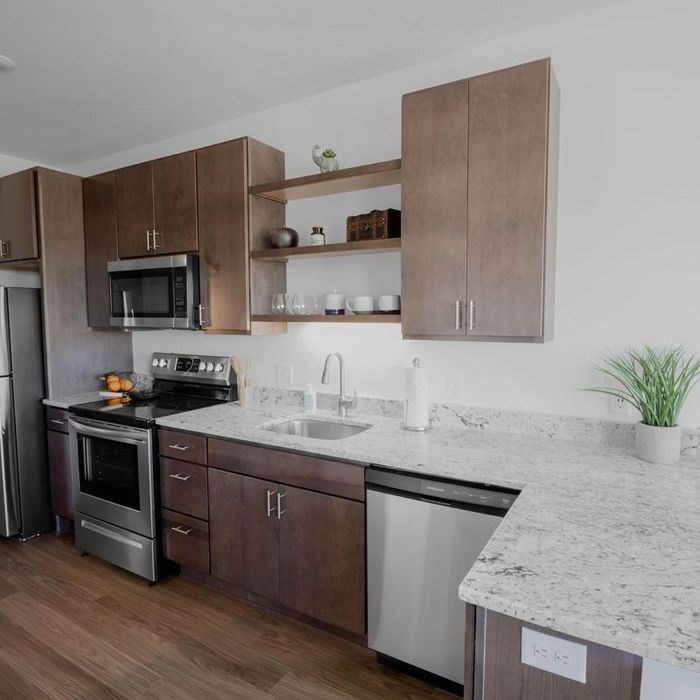 A kitchen with brown cabinets and a marble countertop.