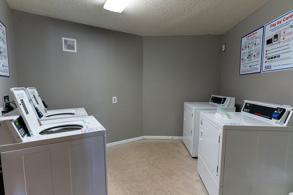 A room with two washing machines and a wall with flyers.