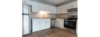 A kitchen with white cabinets and a stainless steel refrigerator.