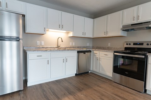 A kitchen with white cabinets and a stainless steel refrigerator.