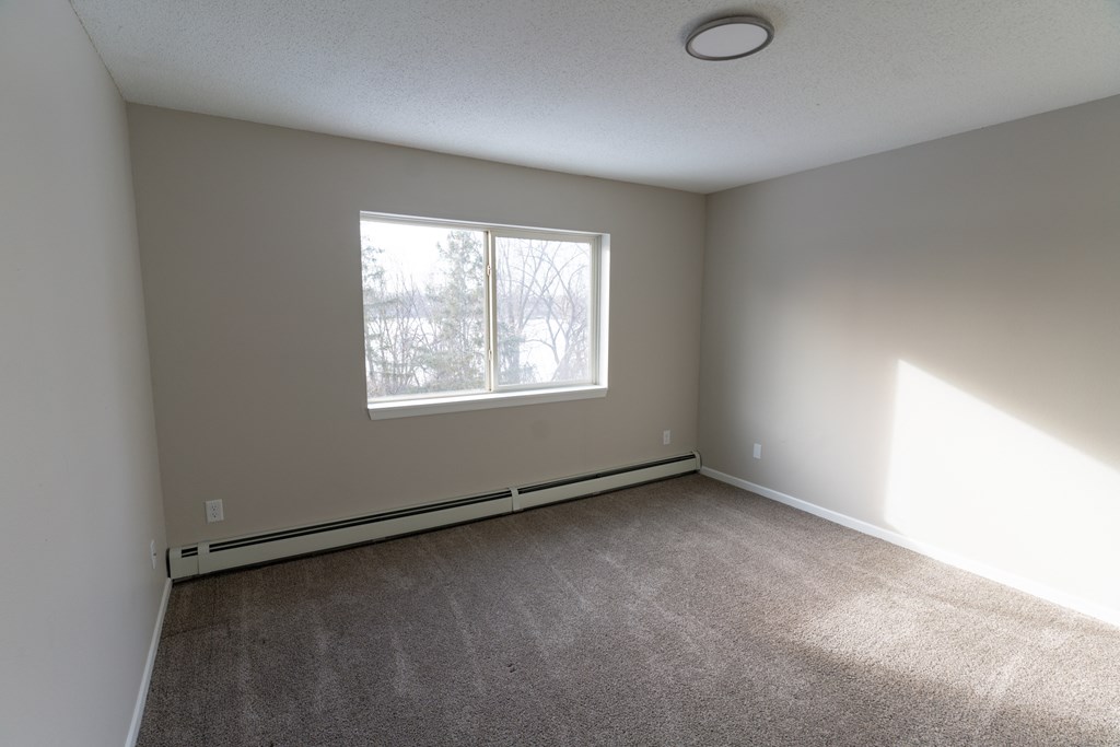 A room with a window and carpeted floor.