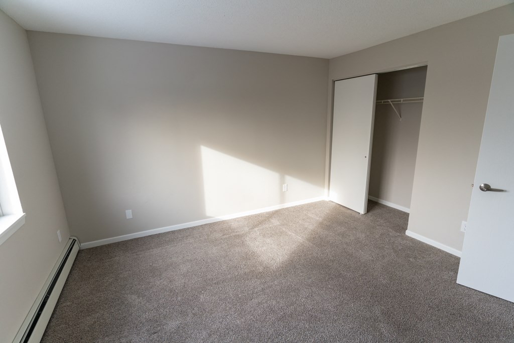 A room with a carpeted floor and a door leading to another room.