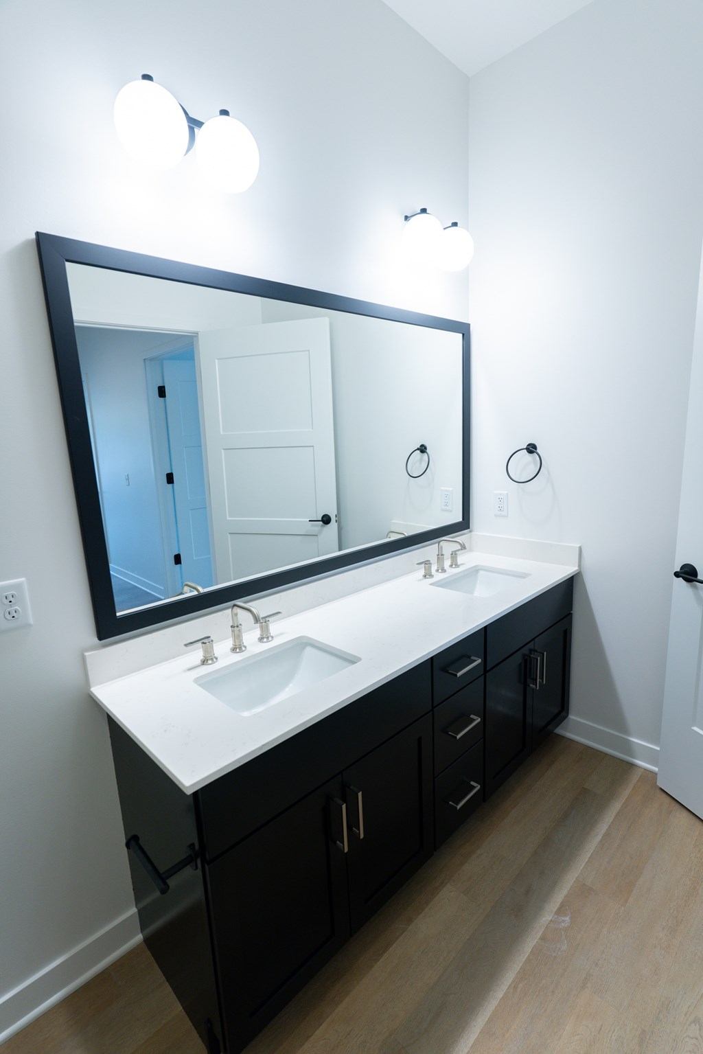 A bathroom with a large mirror above a sink with two faucets.