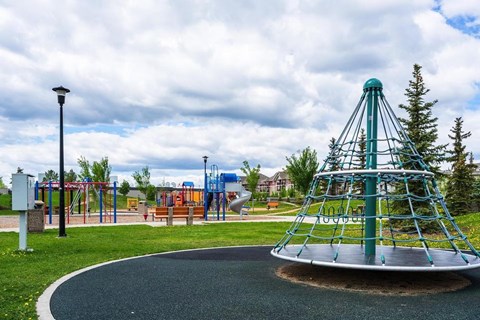 A playground with a green and blue play structure and a slide.
