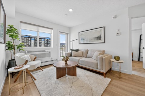 A living room with a white couch, a coffee table, and a large window.