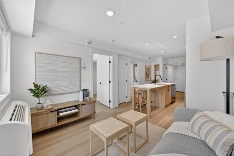 A living room with a grey couch and wooden furniture.