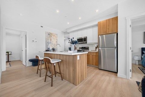 A modern kitchen with wooden cabinets and a stainless steel refrigerator.