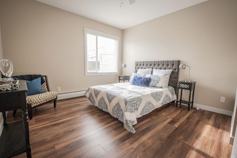 A bedroom with a large bed and a chair.