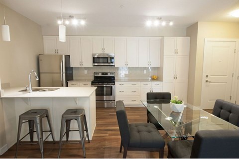 A modern kitchen with a glass table and bar stools.