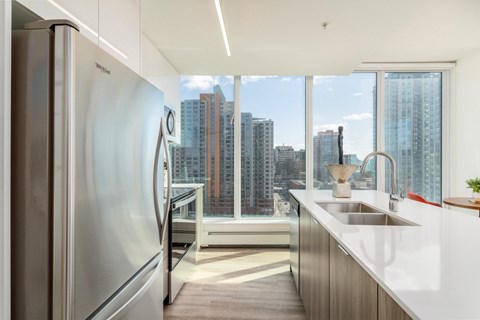 A modern kitchen with a stainless steel refrigerator and a view of the city.