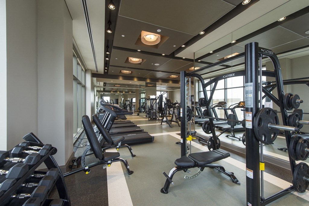 a spacious fitness room with cardio machines and weights