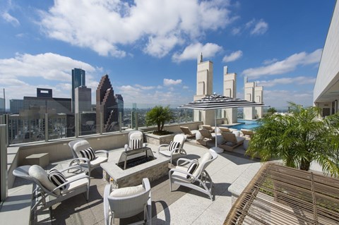 a view of a rooftop deck with a fire pit and lounge chairs by a pool with an open skyline view at market square tower in downtown houston