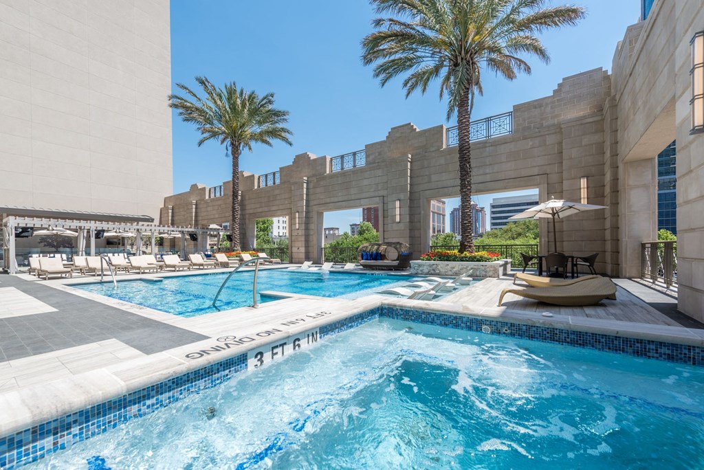 a swimming pool and hot tub with palm trees and seating cabanas