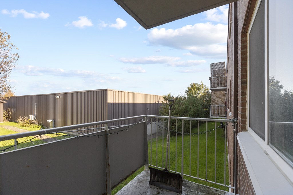 a balcony with a metal railing and a grassy area in the background