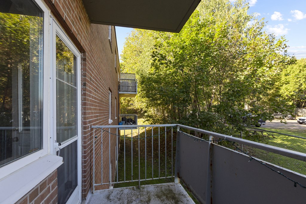 a balcony with a metal railing and a tree with green leaves in the background