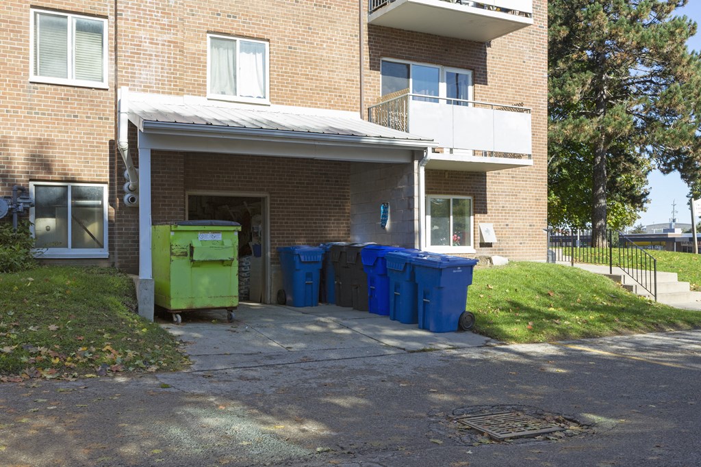 a row of recycling bins in front of a brick building