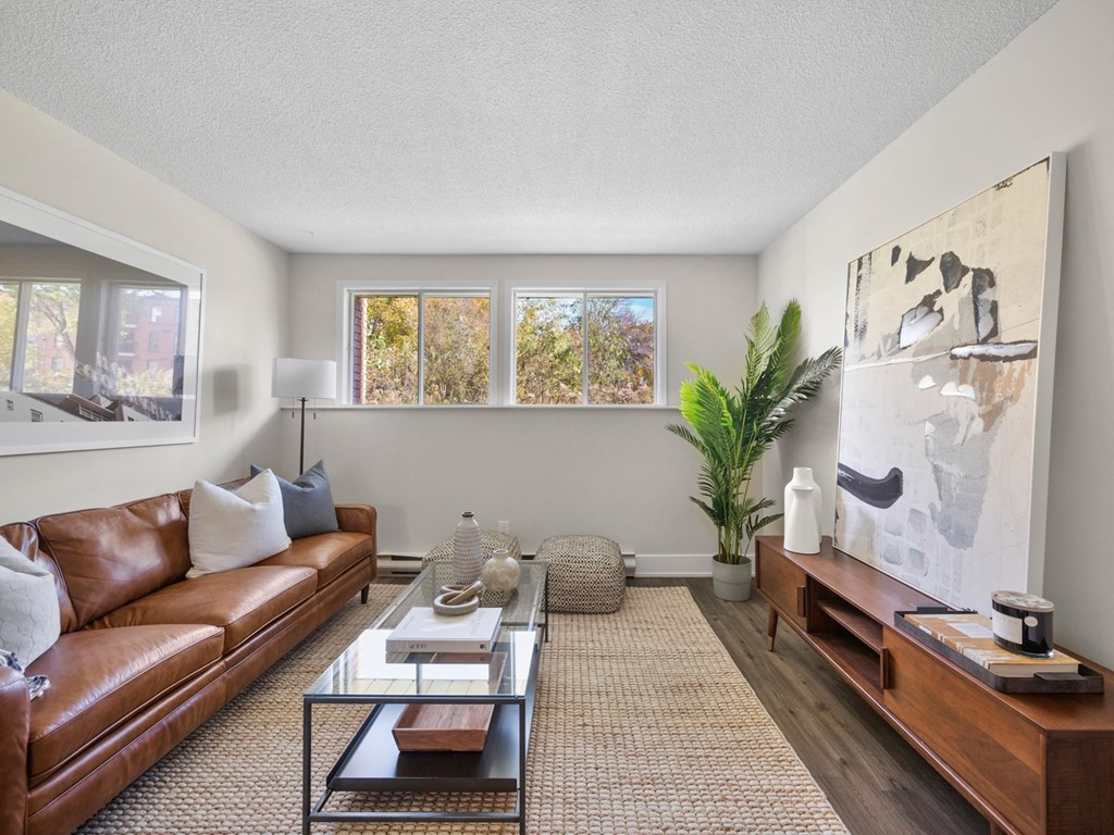 a living room with a brown leather couch and a glass coffee table