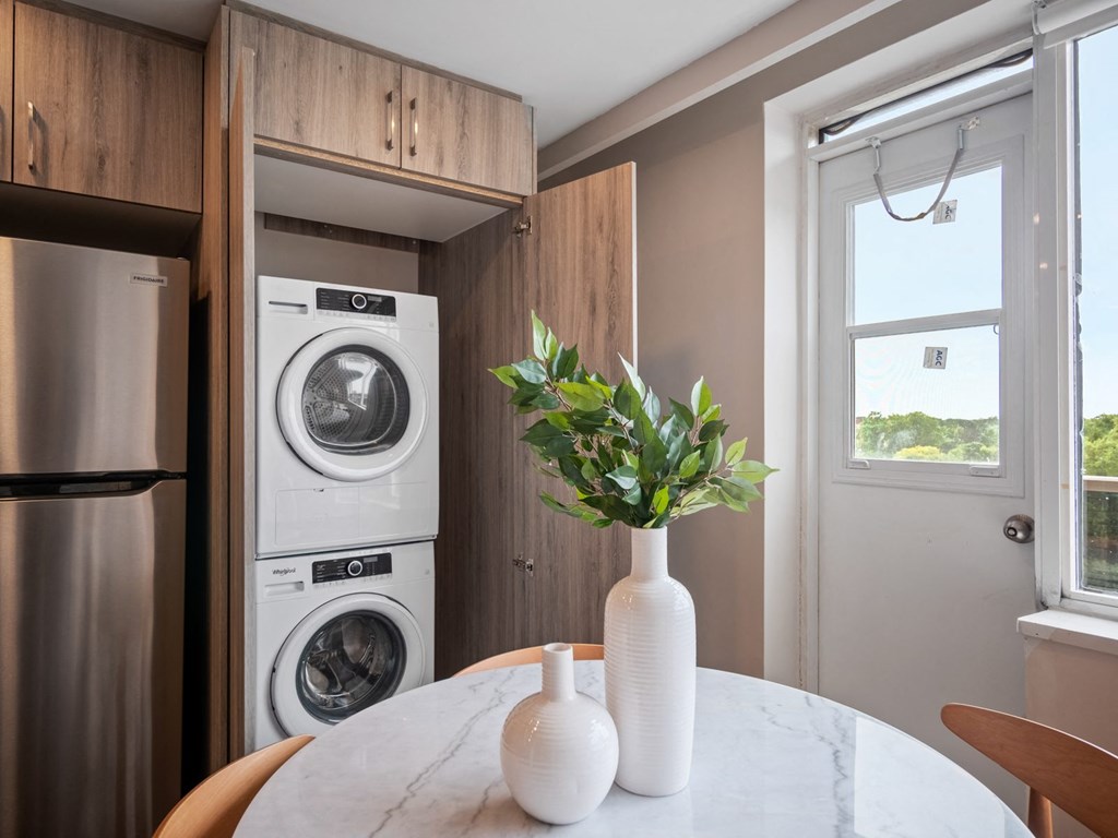 a dining area with a round table and chairs and a washer and dryer in a