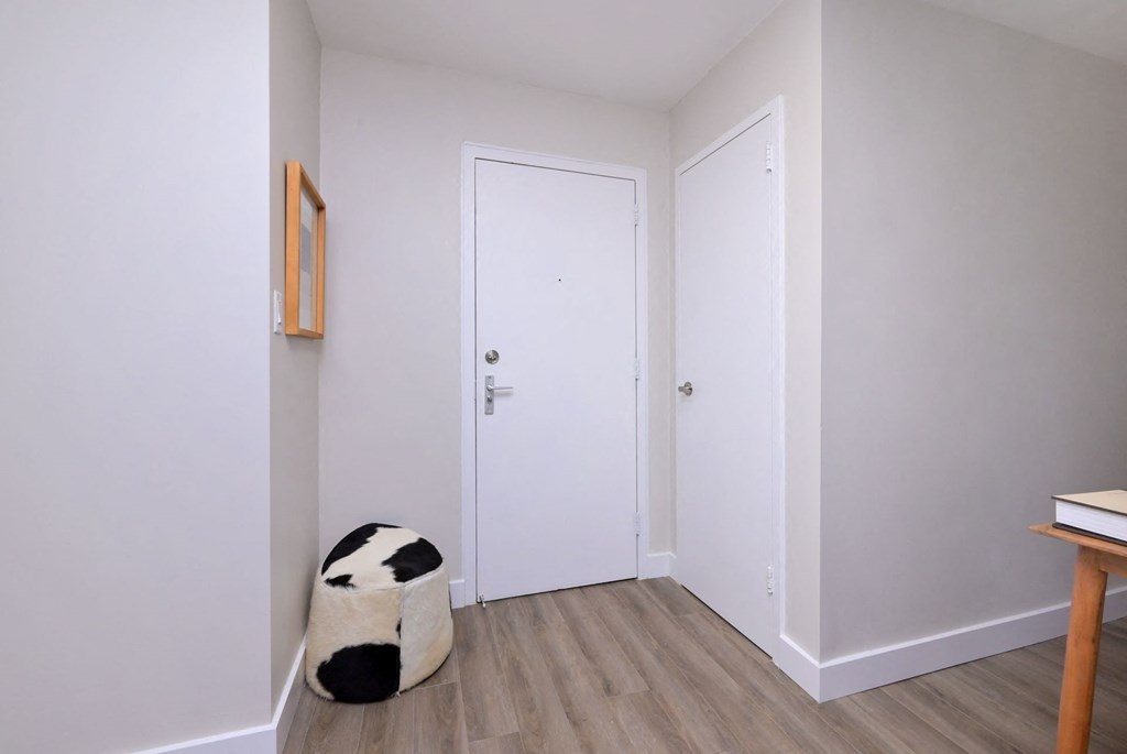 a small white room with a black and white cow stool in the corner