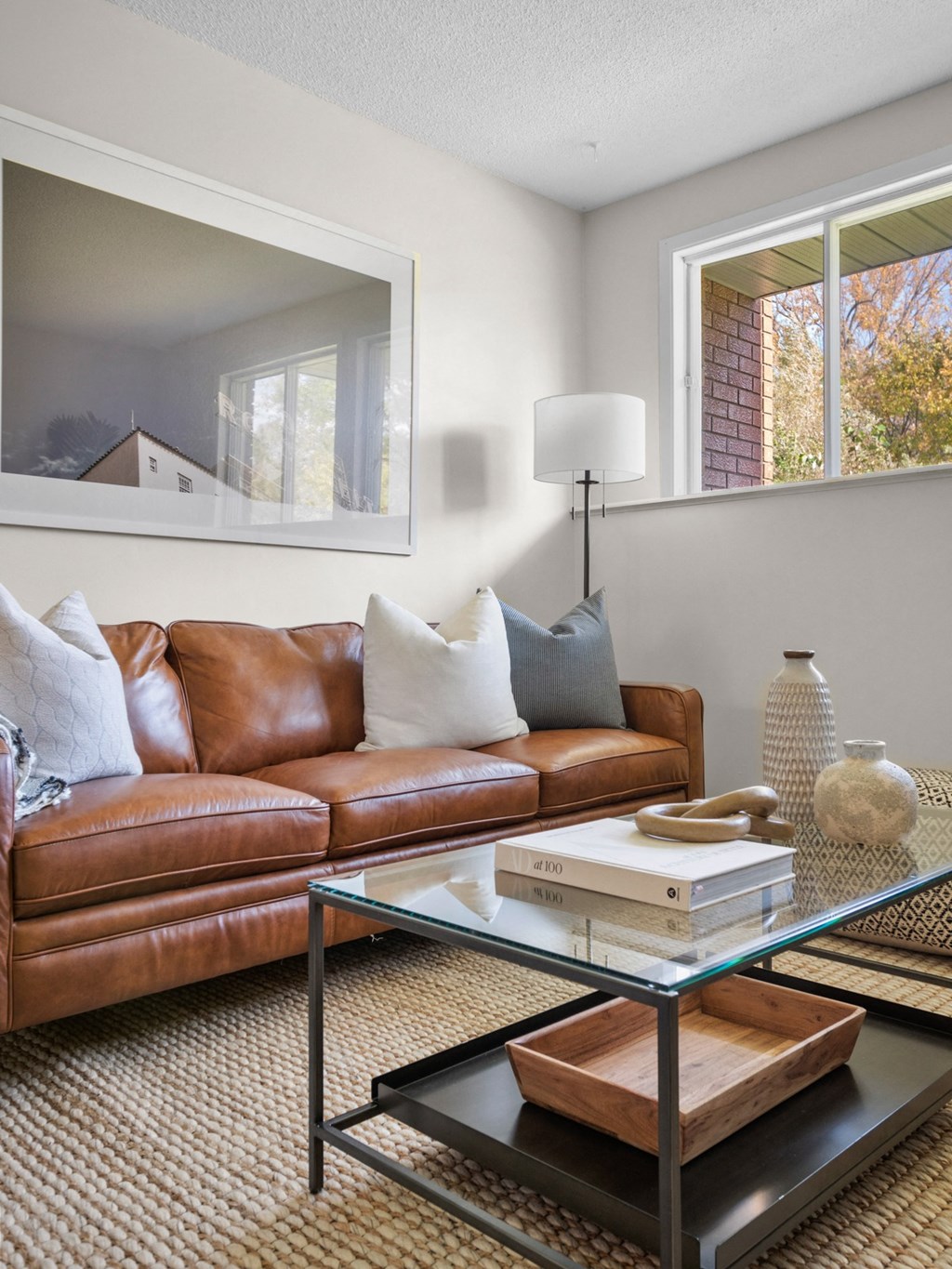 a living room with a brown leather couch and a glass coffee table