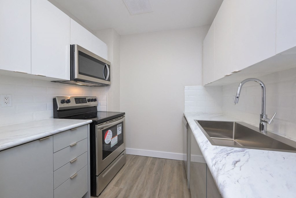 a kitchen with white cabinets and a stainless steel sink