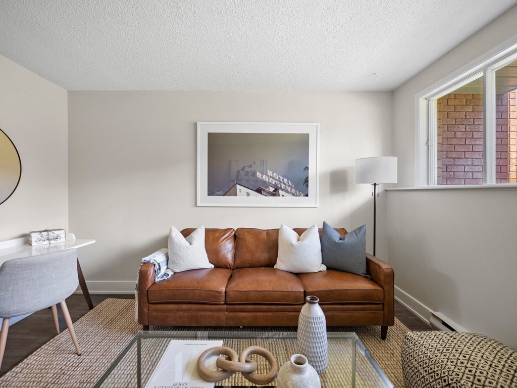 a living room with a brown couch and a glass coffee table
