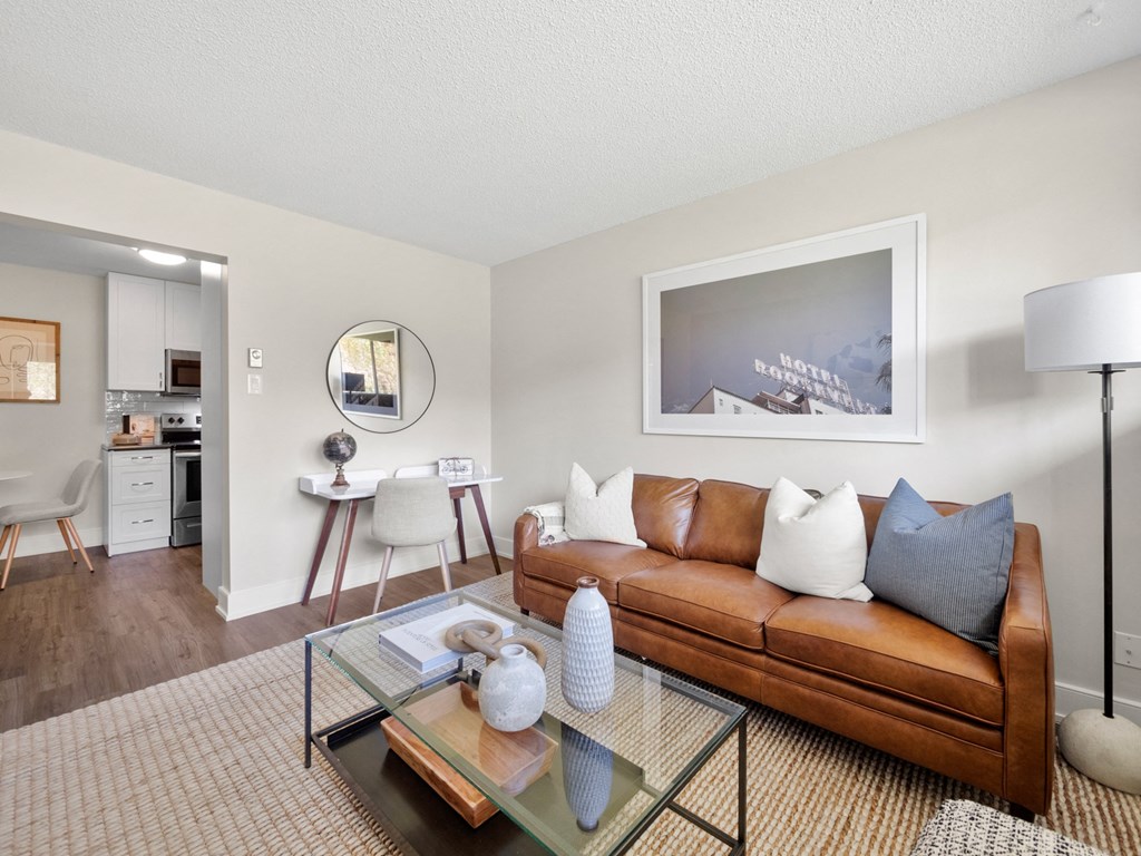 a living room with a brown couch and a glass coffee table