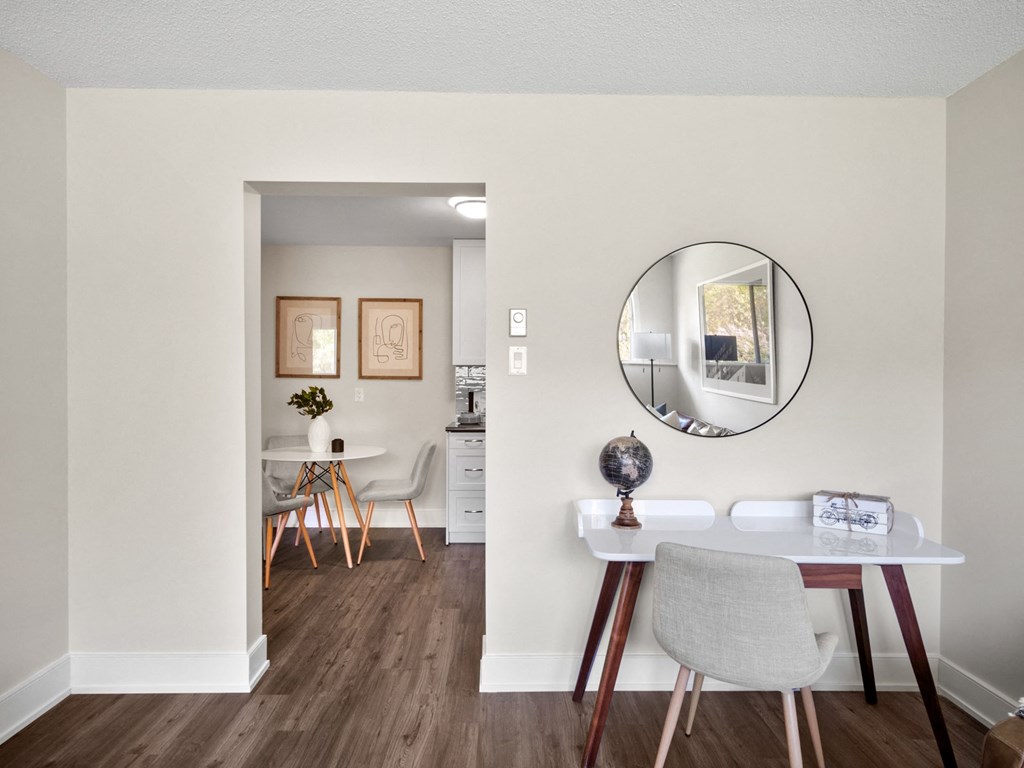 a dining area with a table and chairs and a round mirror on the wall