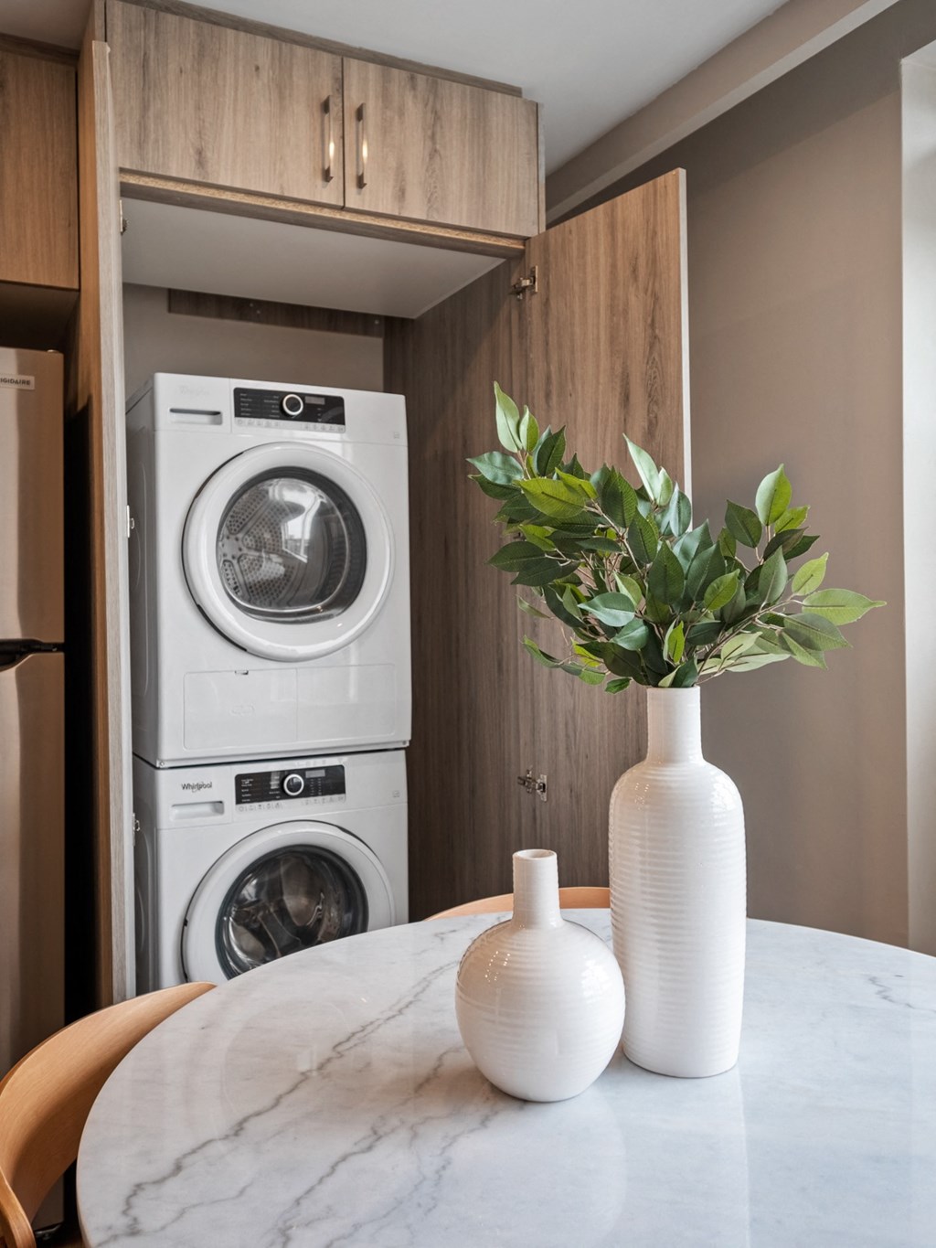 a kitchen with a washer and dryer and a table with a vase on it