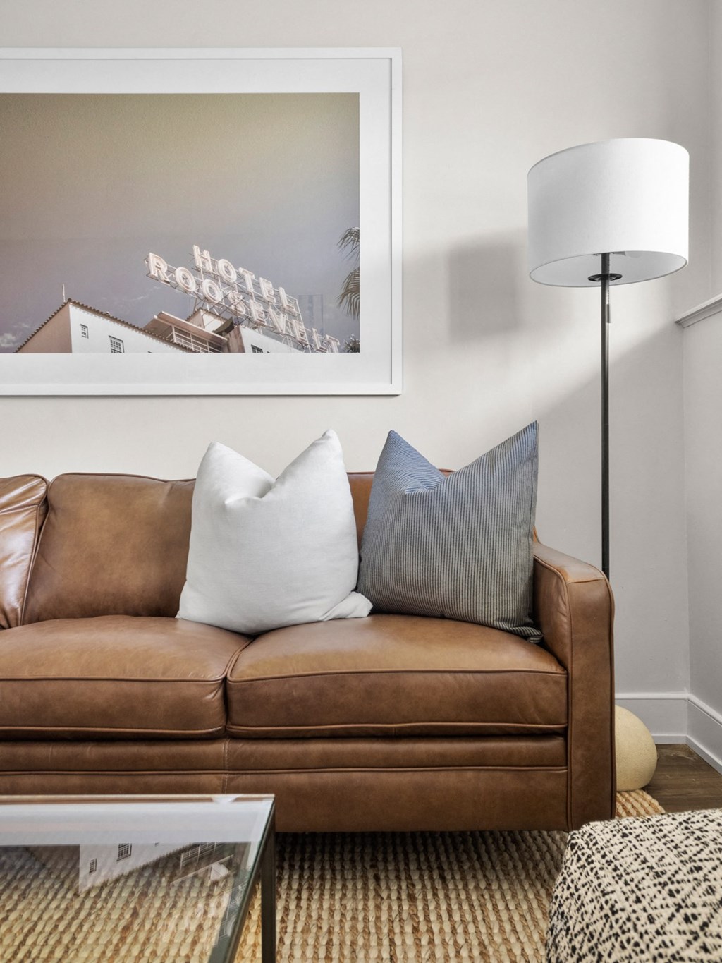 a living room with a brown couch and a white lamp