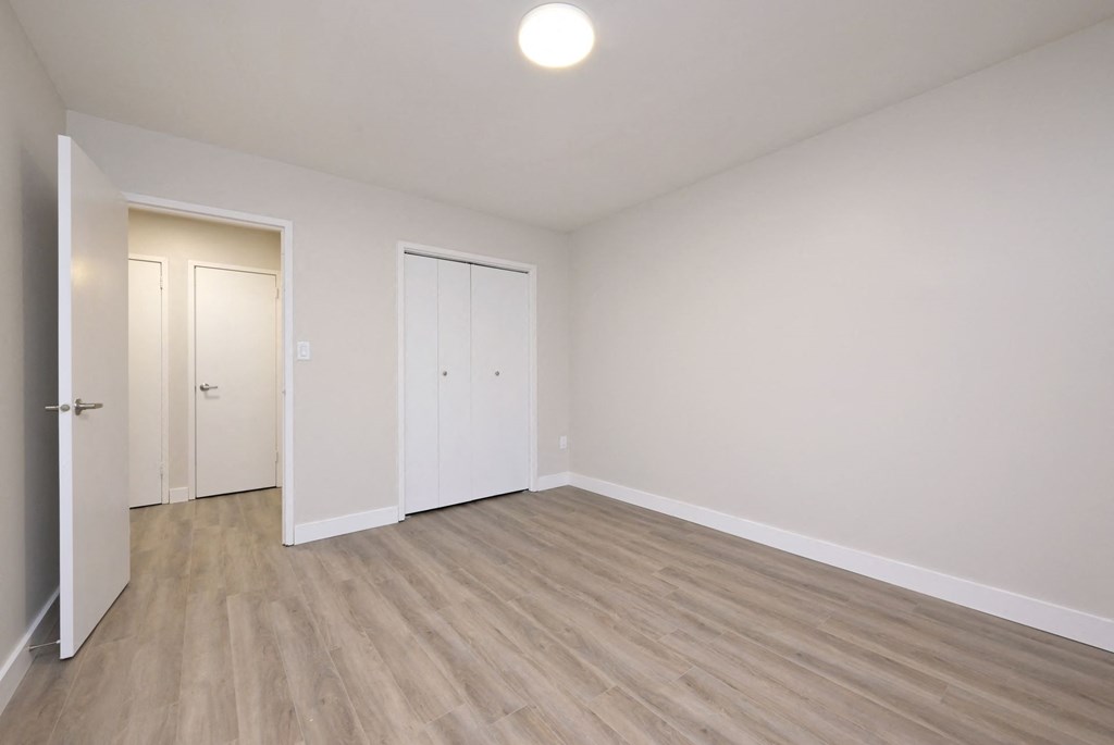 a bedroom with hardwood floors and white walls
