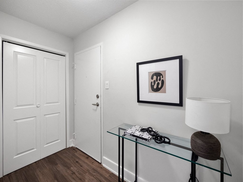a bedroom with white walls and a glass table with a lamp on it