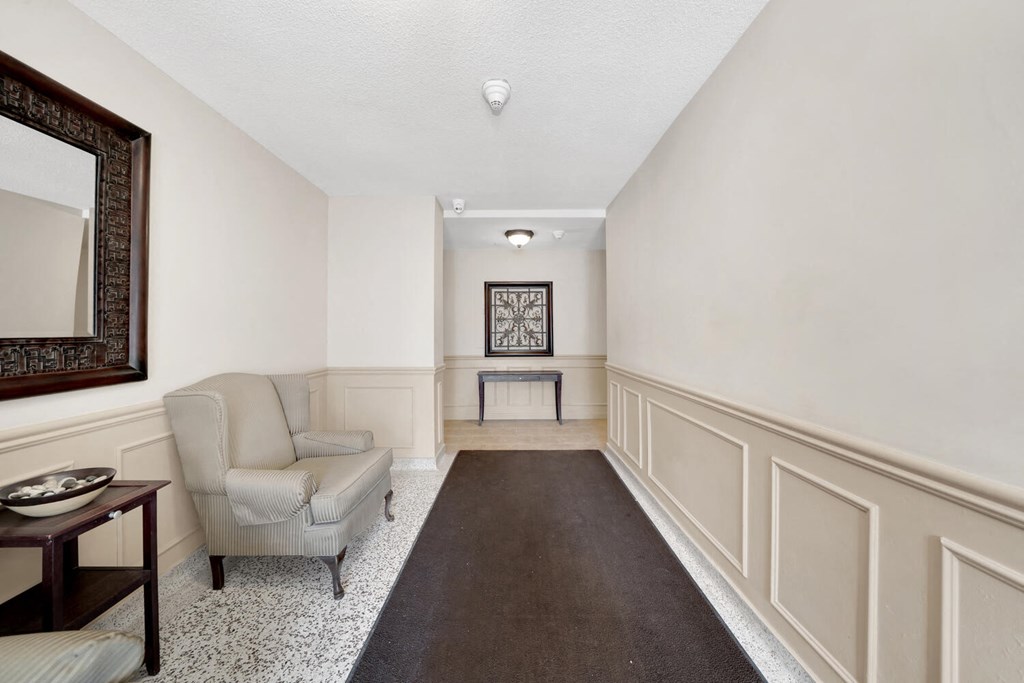 a living room with white walls and a dark rug